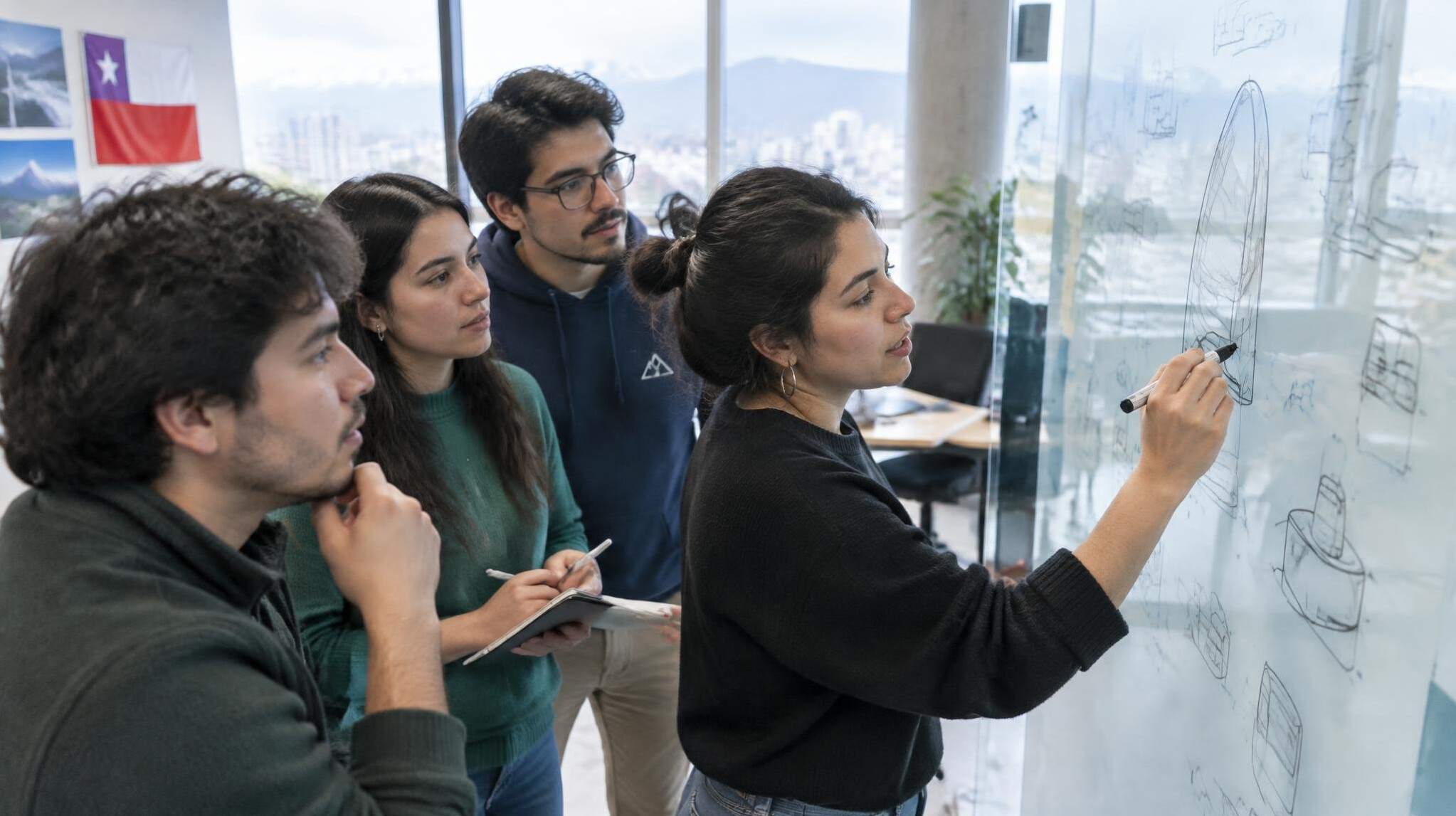 Team of young designers reviewing sketches on a whiteboard in an office
