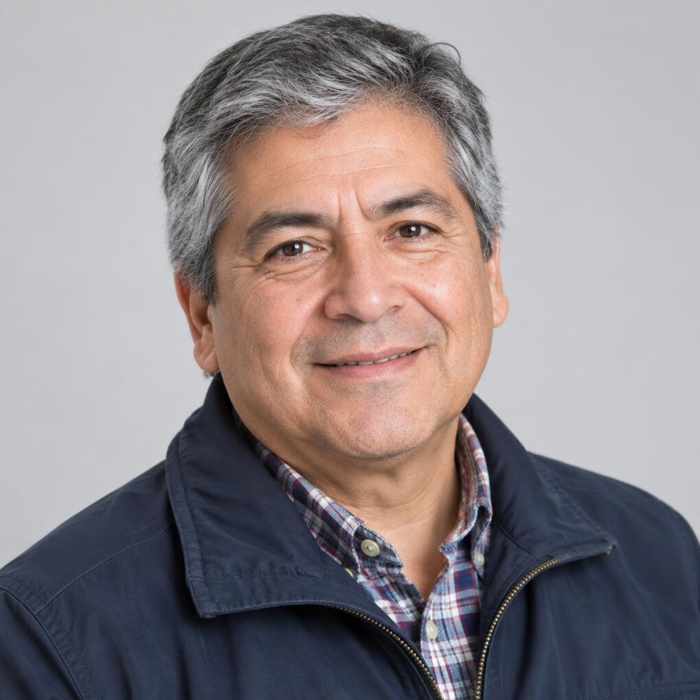 Studio portrait of an older Chilean man with gray hair and a friendly expression